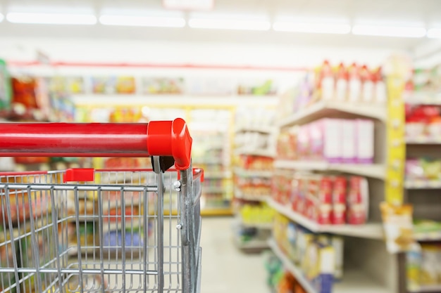 Los estantes de las tiendas de conveniencia tienen un fondo borroso interior con un carrito de compras de supermercado vacío