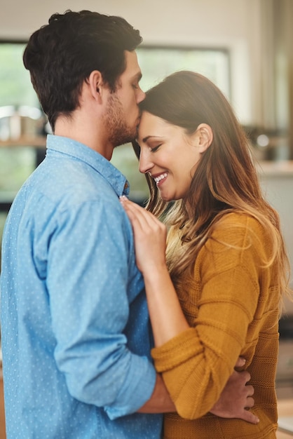 Estaremos juntos para siempre Foto de un joven afectuoso besando a su novia en la frente en la cocina