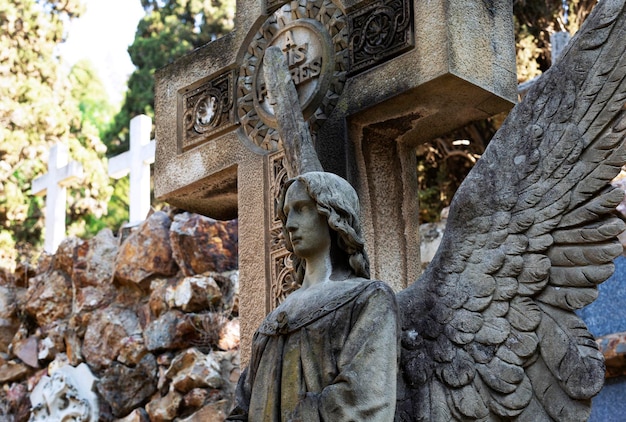 Una estatua de un ángel se encuentra frente a una cruz.