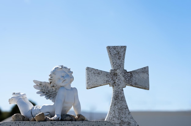 estatua de ángel junto a una cruz