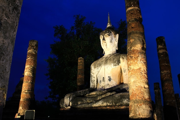 Estatua antigua de Buda en el crepúsculo, Wat Mahathat en el parque histórico de Sukhothai, Tailandia.