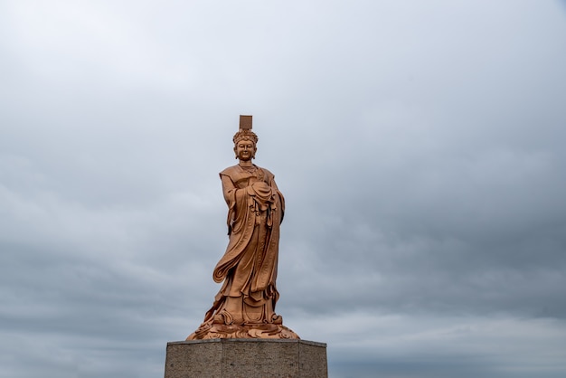 La estatua de bronce de la diosa religiosa china en tiempo nublado