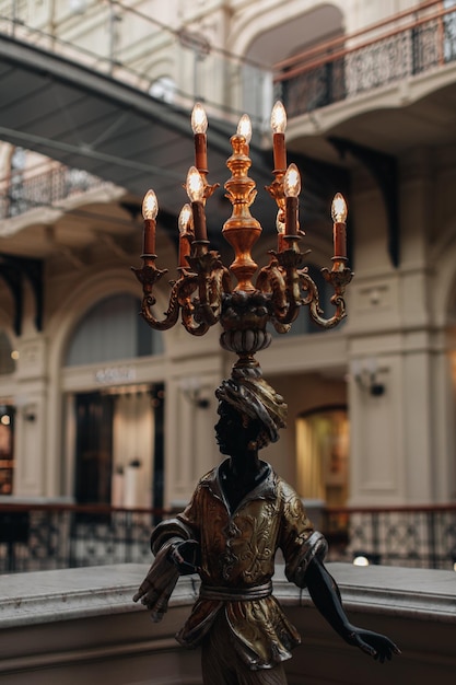 Estatua de bronce de metal vintage de un hombre con una lámpara quemando velas en un interior clásico