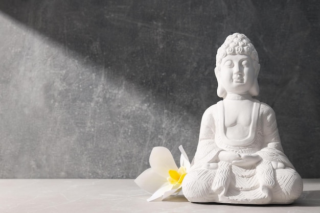 Estatua de Buda y flor sobre fondo gris espacio para texto