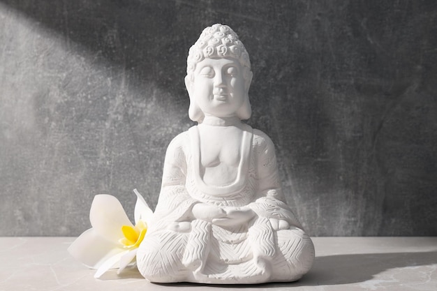 Estatua de Buda y flor sobre fondo gris