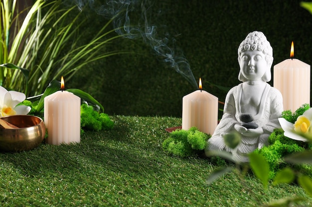 Estatua de Buda flor velas incienso palo y hierba sobre fondo verde espacio para texto