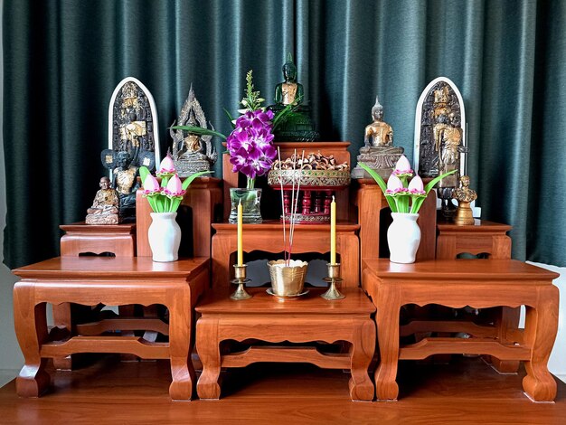 Estatua de Buda en la mesa del altar consagrado con flores sobre fondo verde Bangkok Thailand