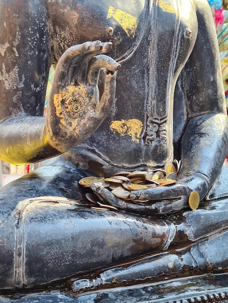 estatua de Buda de muchas caras con donaciones de monedas en un templo tailandés