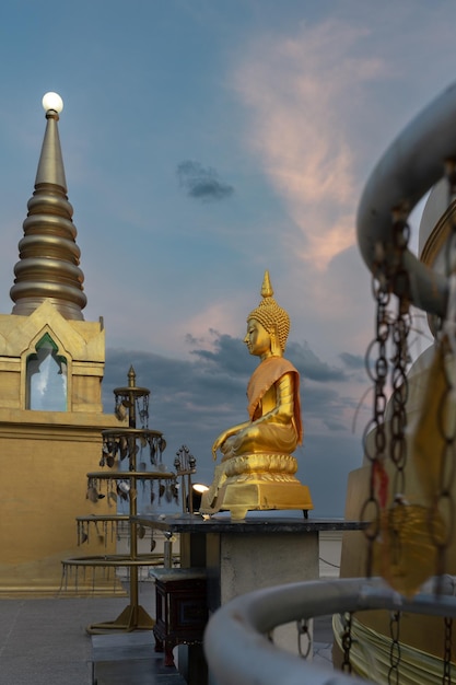 Estatua de Buda de oro cerca de la Pagoda Khao Hua Jook contra el cielo del atardecer Koh Samui Tailandia