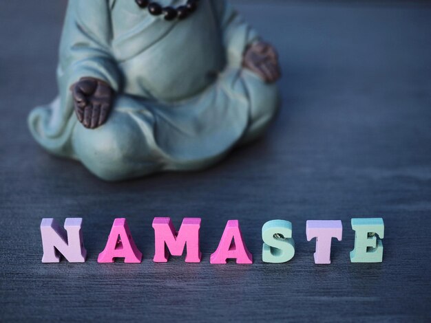 Una estatua de buda padmasana está al lado de la palabra NAMASTE Concepto de yoga Signo de Namaste