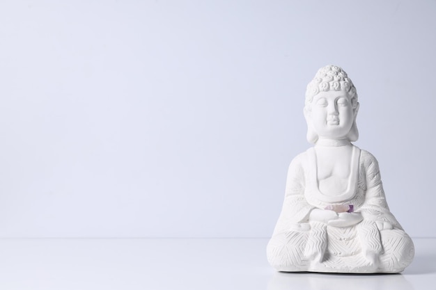 Estatua de Buda y piedras sobre fondo blanco, espacio para texto