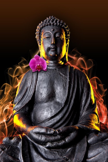 Foto estatua de buda con resplandor y orquídea contra fondo negro