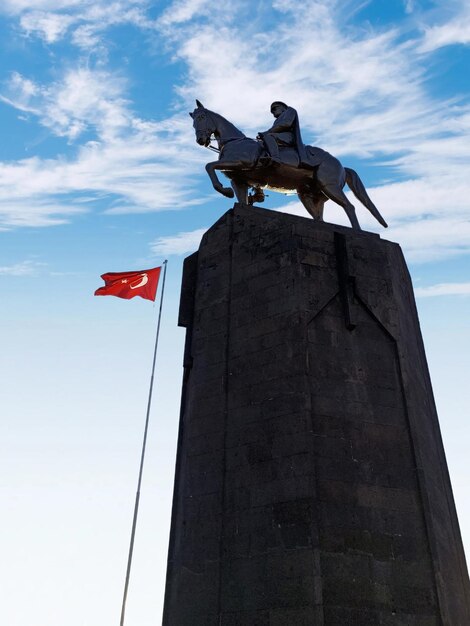 Foto una estatua de un caballo y una bandera roja con una estatua de un hombre