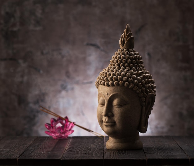 Estatua de cabeza de Buda, incienso y decoración de flores de loto. Concepto de budismo y meditación.