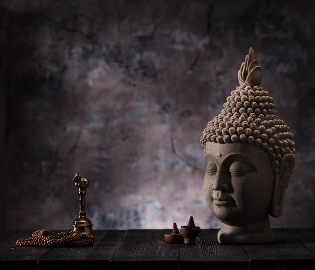 Estatua de cabeza de Buda, incienso y rosario de cuentas de sándalo. Concepto de budismo y meditación.