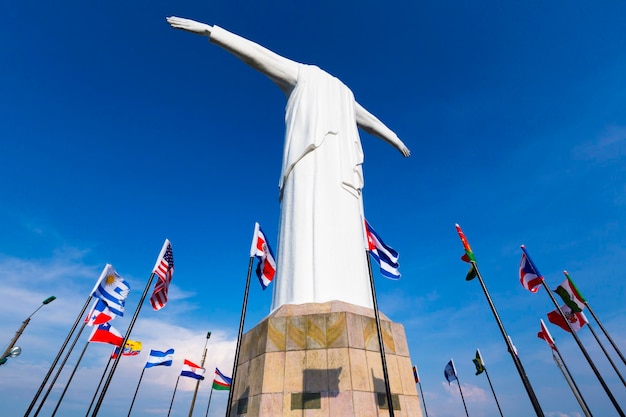 Foto estatua de cristo del rey de cali con banderas del mundo y cielo azul colombia