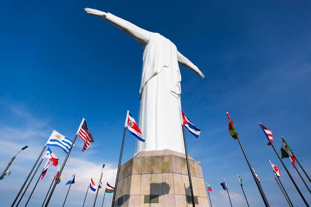 Estatua de Cristo del Rey de Cali con banderas del mundo y cielo azul Colombia