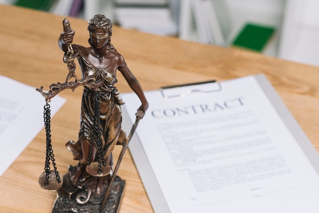 Foto estátua da justiça sobre a mesa com papel de contrato