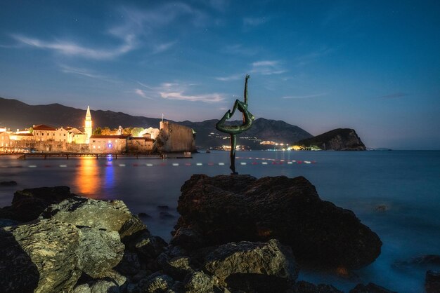 Foto estátua de bailarina e cidade velha de budva no fundo, em montenegro