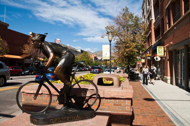 Foto estátua de bronze de ciclista em uma calçada na cidade