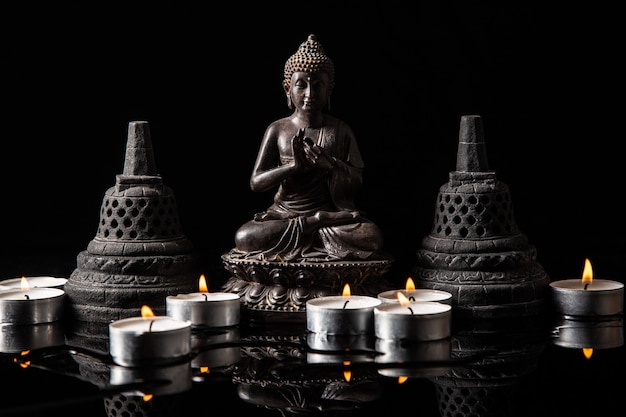 Estátua de Buda sentado em meditação, com velas e sinos budistas