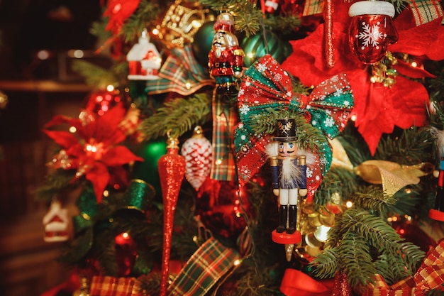 Estátua de madeira do quebra-nozes do soldado de brinquedo que pendura na árvore de Natal decorada, estilo do vintage. Ornamento tradicional da estatueta dos quebra-nozes do feriado do Natal.