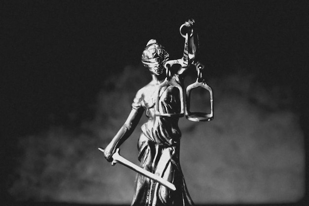 Foto estátua de temis justiça com escamas em fundo escuro com fumaça conceito legal e jurídico