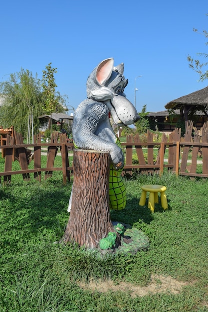 Estátua de uma fada-lobo Lobo perto de um tronco com sapos