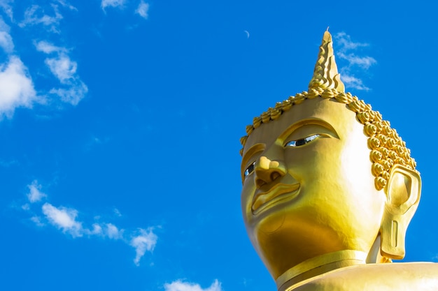 Estátua dourada grande de Buddha com fundo do céu azul.