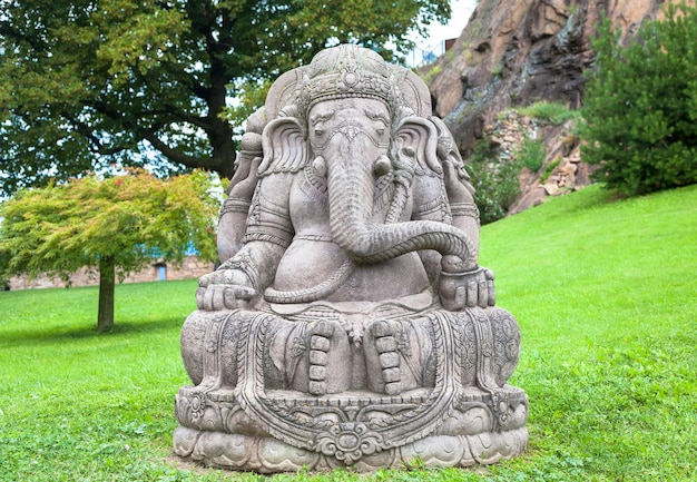 Estatua de Ganesha, hecha de piedra, con un hermoso jardín de montaña en segundo plano.