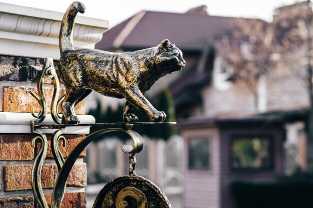 Estatua de un gato de bronce en la puerta de entrada a la casa