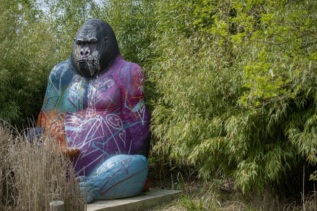 Una estatua de gorila se sienta en un jardín con un bosque de bambú detrás.