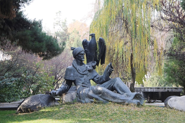 Una estatua de un guerrero con un águila en el pecho se sienta en un parque.