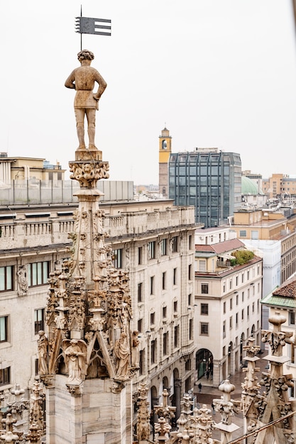 Estatua de un hombre con una bandera en la torre del duomo italia milán