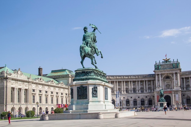 Una estatua de un hombre a caballo se encuentra frente a un edificio con un cielo azul.