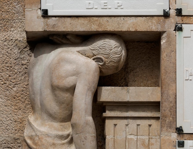 Una estatua de un hombre con la cabeza hacia abajo y la palabra de. p en el letrero.