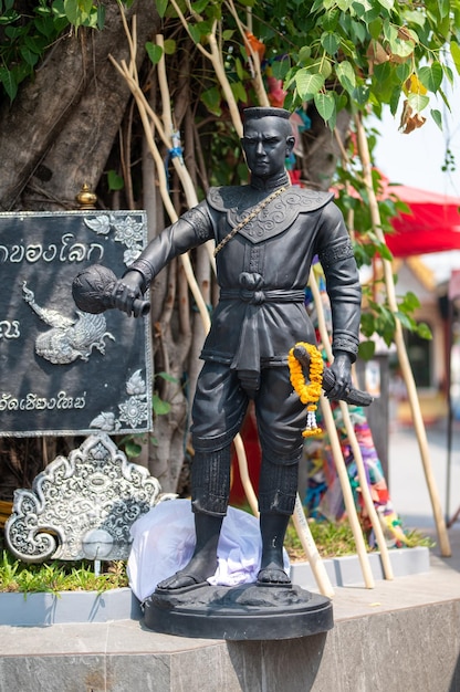 Una estatua de un hombre vestido de negro se encuentra frente a un letrero que dice 'chiang mai'