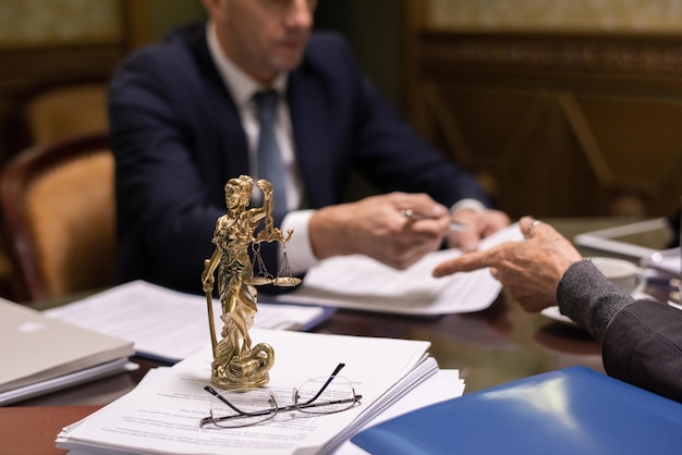 Estatua de la justicia y anteojos en una pila de papeles jurídicos