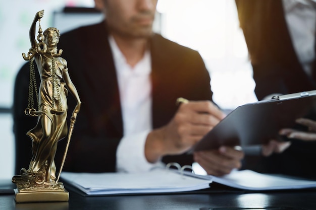 Estatua de la justicia con escamas y martillo de subasta la reunión del equipo en el bufete de abogados detrás del concepto de ley en la oficina