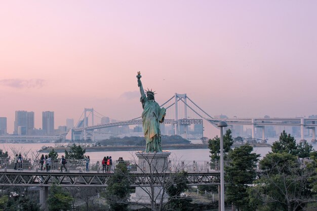 Estatua de la libertad con el puente del arco iris en el parque costero de Odaiba