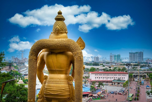 Foto estatua de lord muragan y entrada con nube azul del cielo durante el día en las cuevas batu en kuala lumpur, malasia