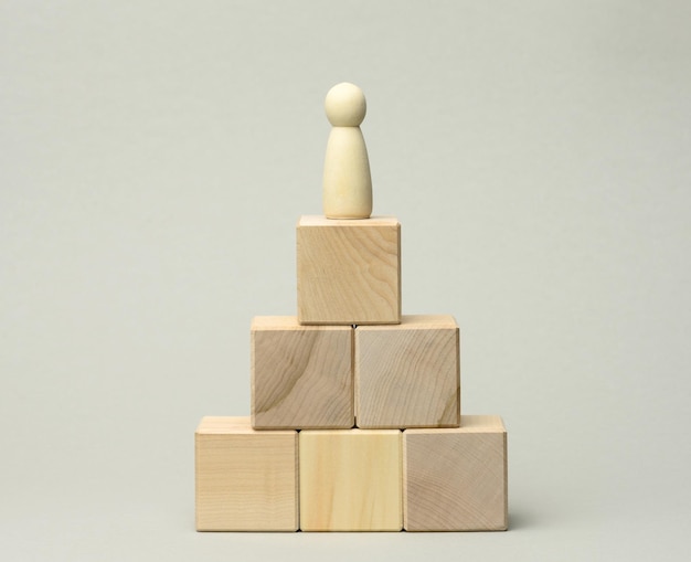 Estatua de madera de un hombre en la parte superior de la pirámide el concepto de crecimiento profesional objetivo lograr