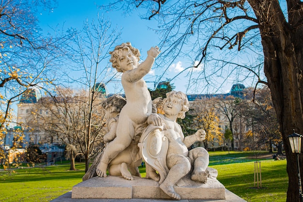 Estatua de mármol blanco de tres niños desnudos angelicales en el parque Bruggarten en un día soleado en Viena Austria