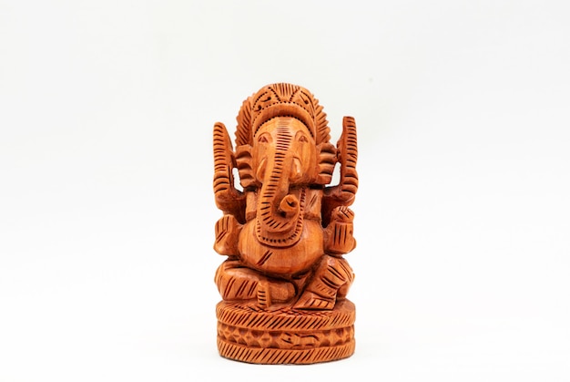 Foto estatua en miniatura de madera del dios hindú ganesha sobre una superficie blanca