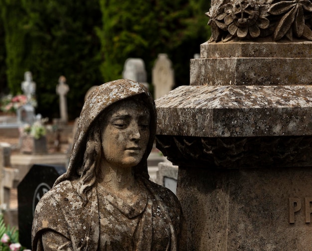 Una estatua de una mujer se encuentra junto a un pilar con un diseño floral.