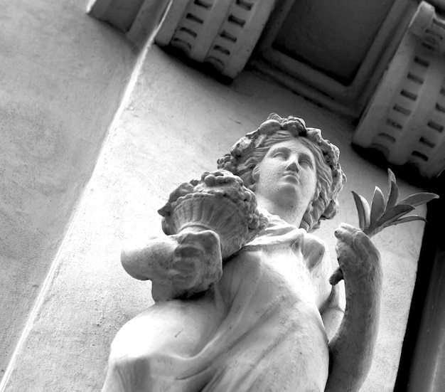 Una estatua de una mujer con una flor en la mano.