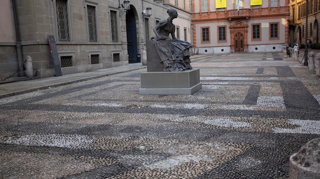 Una estatua de una mujer con un vestido se encuentra en una plaza frente a un edificio con un letrero que dice "la palabra" en él.