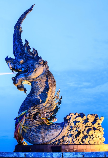 La estatua de Phaya Naga roció agua y el cielo de la tarde.