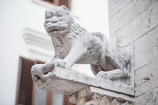 una estatua de piedra de un dragón con un edificio en el fondo