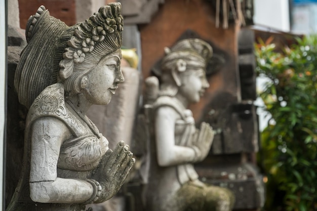 Estatua de piedra con las manos en una oración en la entrada del templo en Bali Indonesia